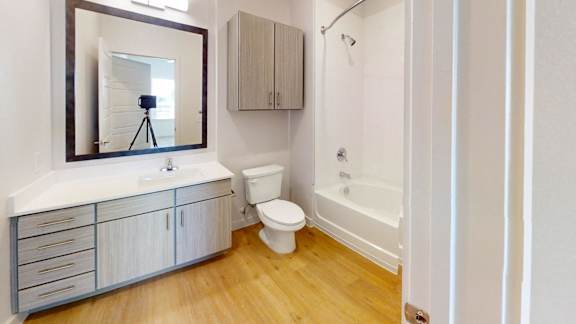 A bathroom with a wooden floor and white walls.