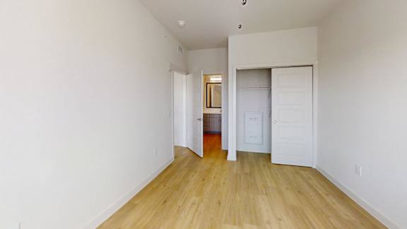 A room with white walls and wooden flooring with two doors.
