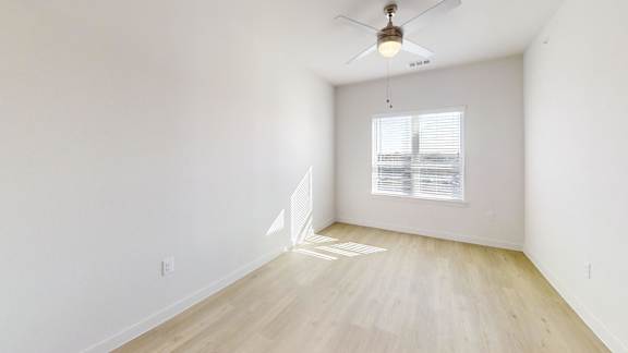 A room with a ceiling fan and a window with blinds.