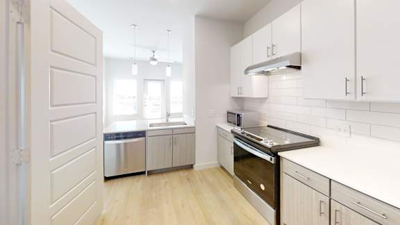 Galley kitchen with stainless appliances and subway tile at Matador Apartments, Texas
