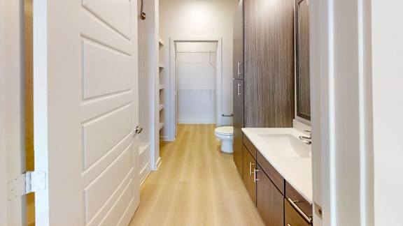 A long hallway with a toilet and sink at the end.