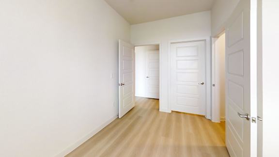 A hallway with white doors and wooden floors.