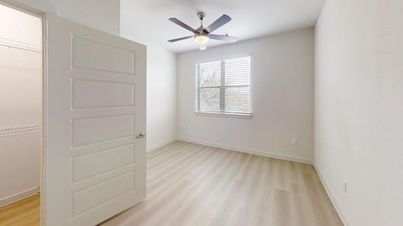 A room with a ceiling fan and a window with blinds.