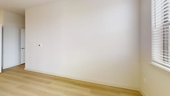 A room with a white wall and wooden floor.