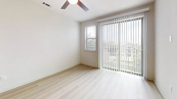 A room with a sliding glass door leading to a balcony.