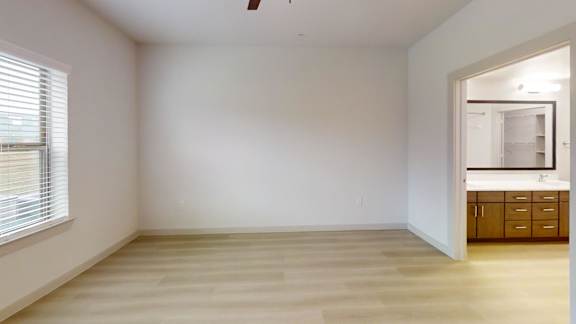 A room with a wooden floor and a window with blinds. at Bridge at Saffron Apartments, Austin