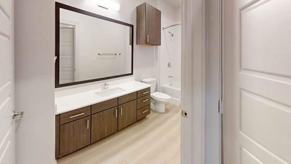 A bathroom with a sink, toilet and mirror. at Bridge at Saffron Apartments, Austin