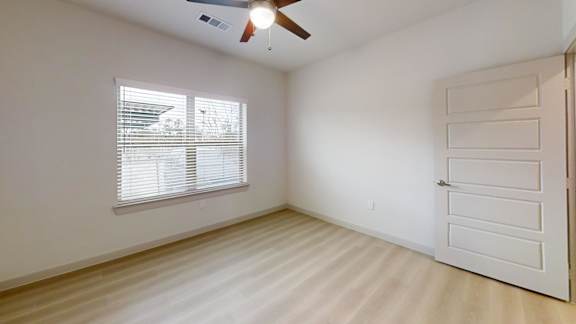 A room with a white door and a window with blinds. at Bridge at Saffron Apartments, Austin, Texas