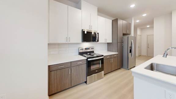 A modern kitchen with wooden cabinets and stainless steel appliances. at Bridge at Saffron Apartments, Texas