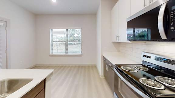 A kitchen with a stove, microwave, and sink. at Bridge at Saffron Apartments, Austin, TX, 78717