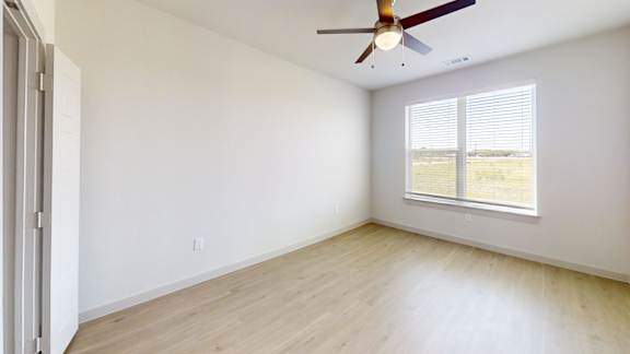 A room with a ceiling fan and a window with blinds.