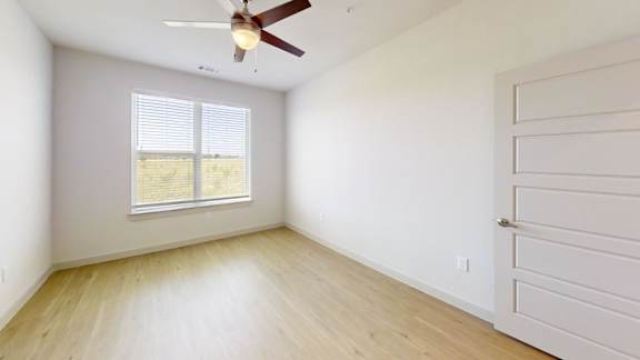 A room with a ceiling fan and a window with blinds.