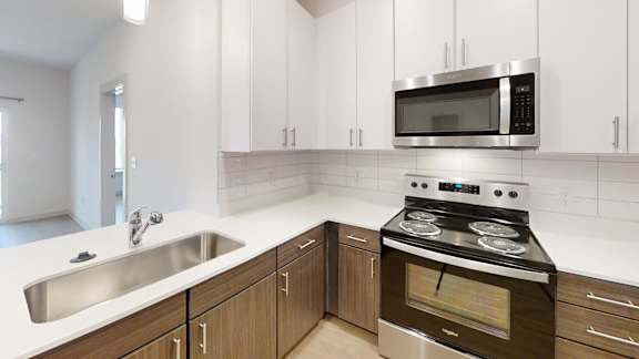 A modern kitchen with a stove, sink, and cabinets.