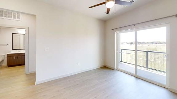 A room with a sliding glass door leading to a balcony.