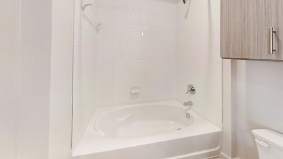 A white bathroom with a tub and toilet.