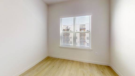 A room with a window and wooden flooring.