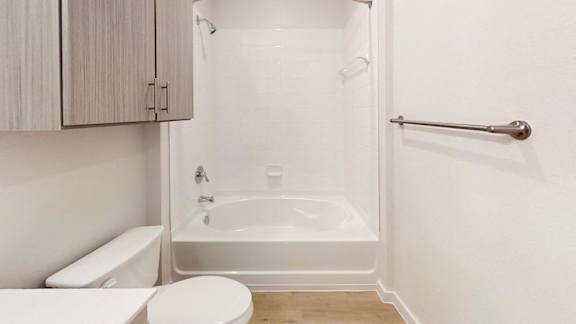 A white toilet sits next to a white bathtub in a bathroom.