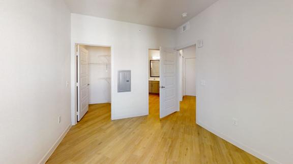 A room with white walls and wooden floors with two doors.