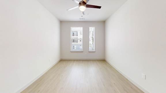 A room with a ceiling fan and a window with blinds.