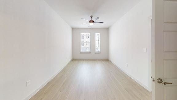 A room with a ceiling fan and a door.