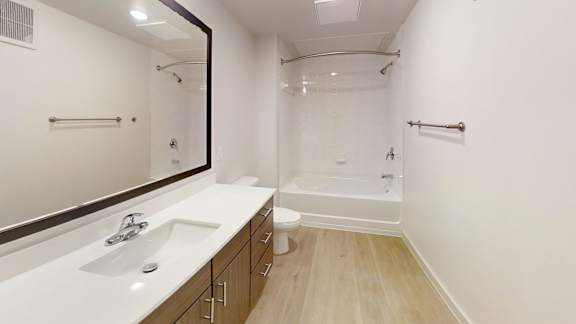 A white bathroom with a sink, mirror, and bathtub.