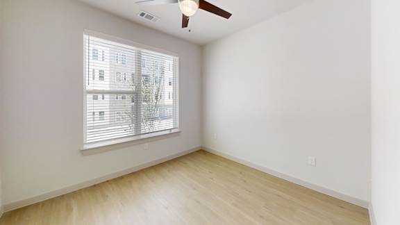 A room with a window and a ceiling fan.