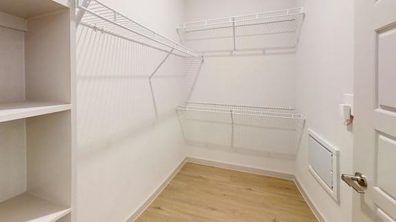 A white walk in closet with shelves and a door.