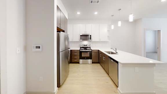 A modern kitchen with stainless steel appliances and wooden flooring.