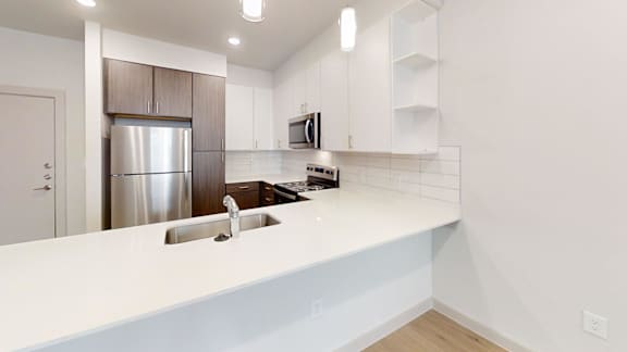 A modern kitchen with a stainless steel refrigerator and white countertops.
