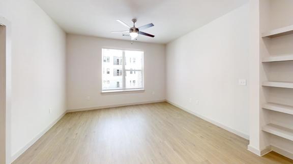 Empty room with a window and a ceiling fan.