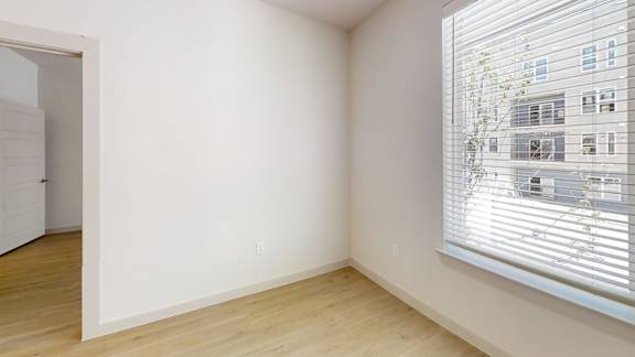 A room with a window showing a building outside.