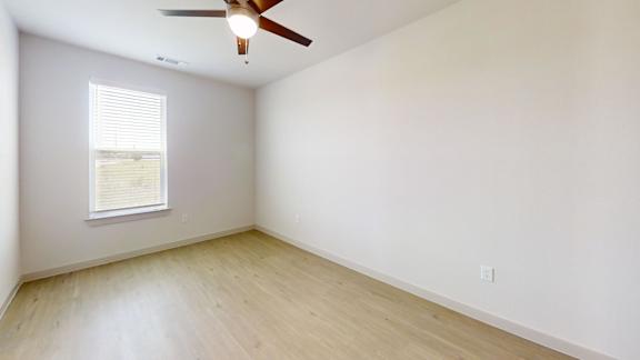 A room with a ceiling fan and a window with blinds.