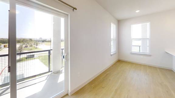 A room with a sliding glass door leading to a balcony.