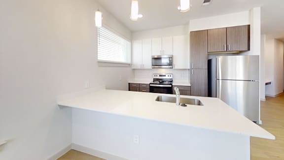 A modern kitchen with a white countertop and stainless steel appliances.