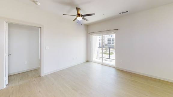 A room with a ceiling fan and sliding glass doors.