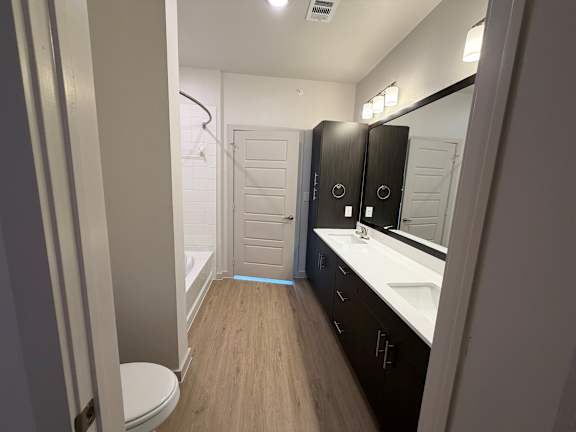 A bathroom with a toilet, sink, and mirror.