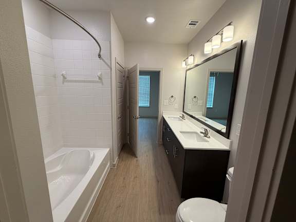 A bathroom with a white tub, sink, and toilet.