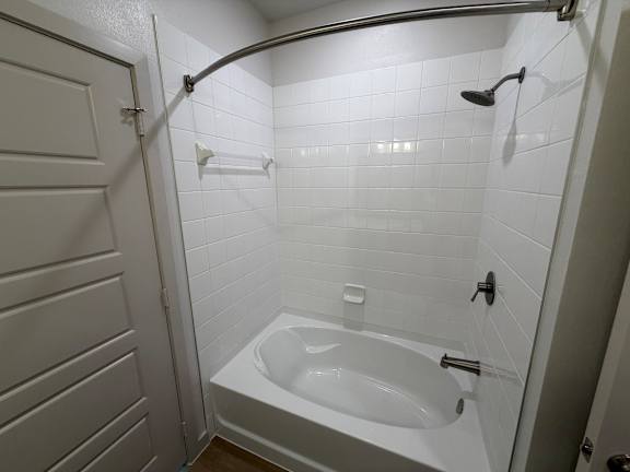 A white bathroom with a white tub and a white door.