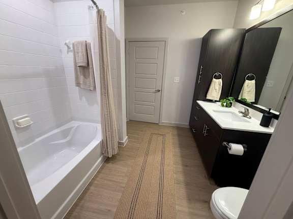 A bathroom with a white tub, sink, and toilet.