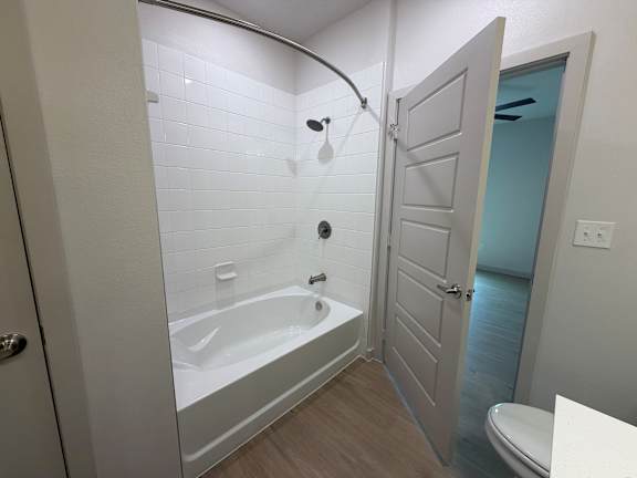 A white bathroom with a tub and toilet.