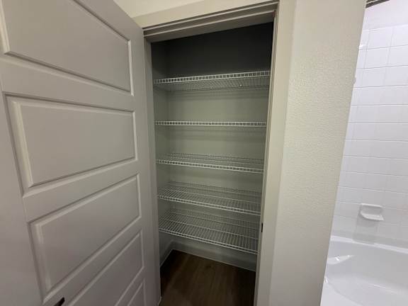 A white door opens to a walk-in pantry with empty shelves.