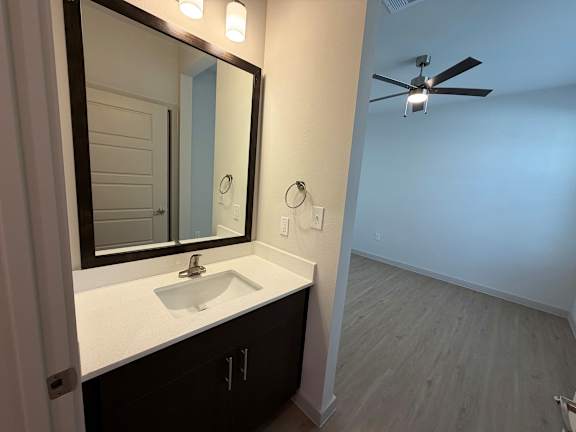 A bathroom with a sink, mirror, and fan.