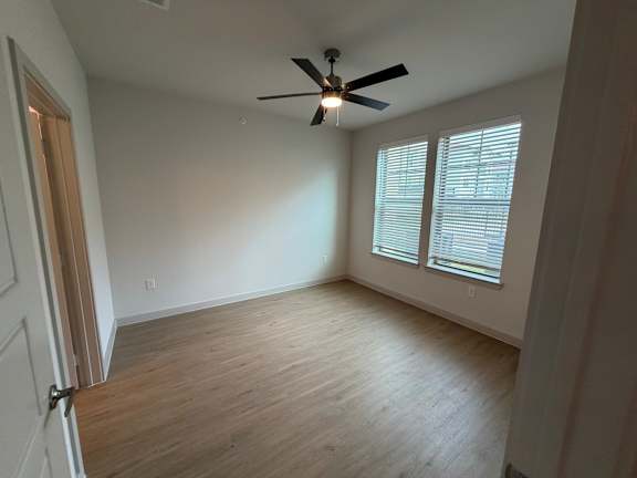 A room with a ceiling fan and wooden flooring.