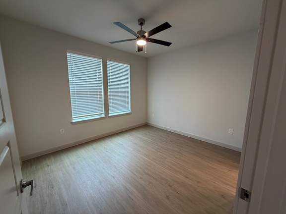 A room with a ceiling fan and a window with blinds.