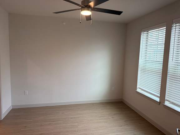 A room with a ceiling fan and a window with blinds.