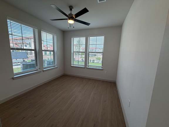 A room with a ceiling fan and wooden flooring.