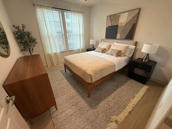A bedroom with a bed, nightstands, and a rug.
