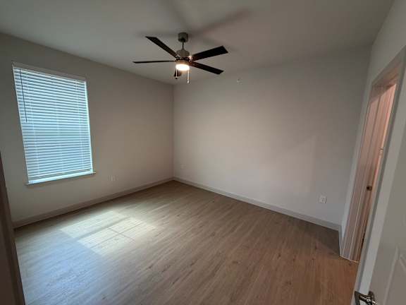 A room with a ceiling fan and wooden flooring.