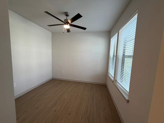 A room with a ceiling fan and wooden flooring.