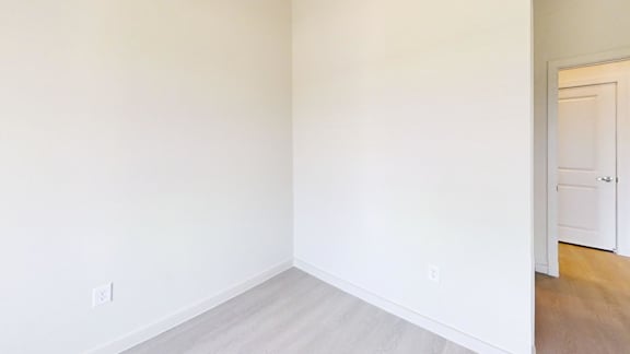 A room with a white door and a light switch on the wall.